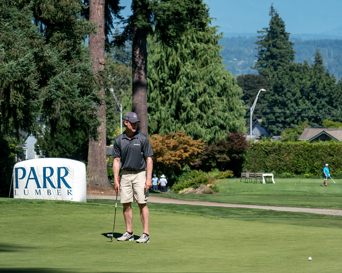 A large Parr Lumber sponsor sign in the background of a golf tournament